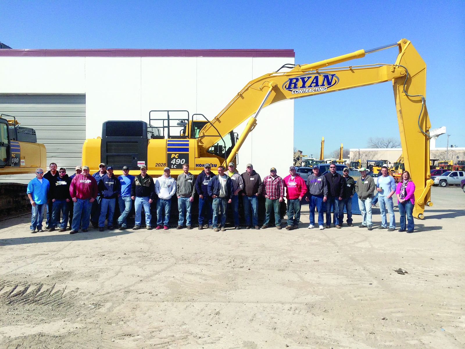 The Ryan Contracting team gathered in front of a new Komatsu PC490 excavator at the shop