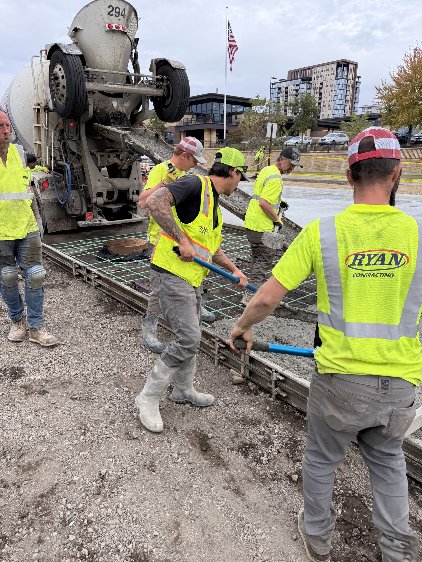 Crew placing concrete over reinforcing mesh from a ready-mix chute