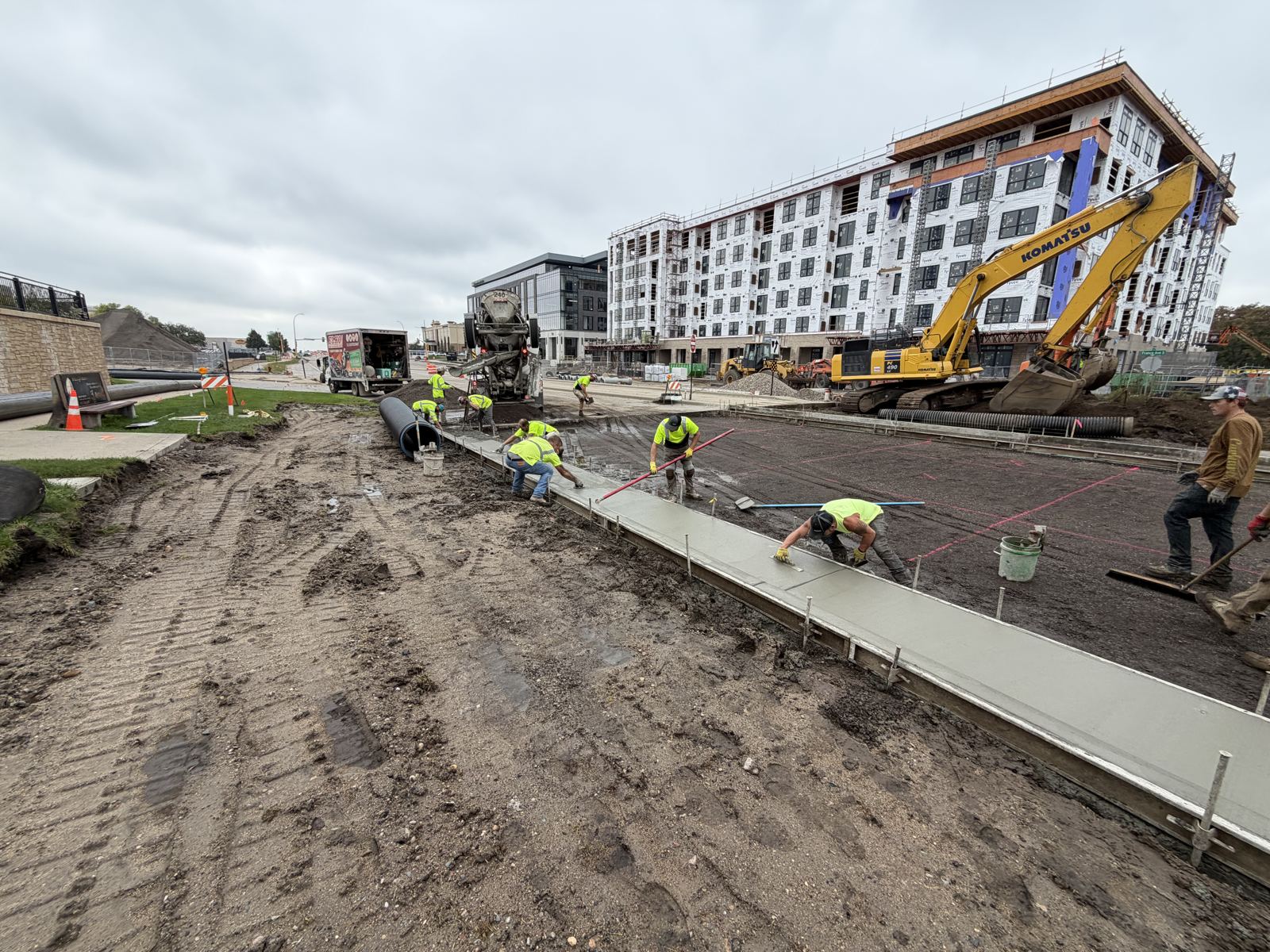 Concrete crew pouring curb and sidewalk on a rebuilt street in front of a new apartment building