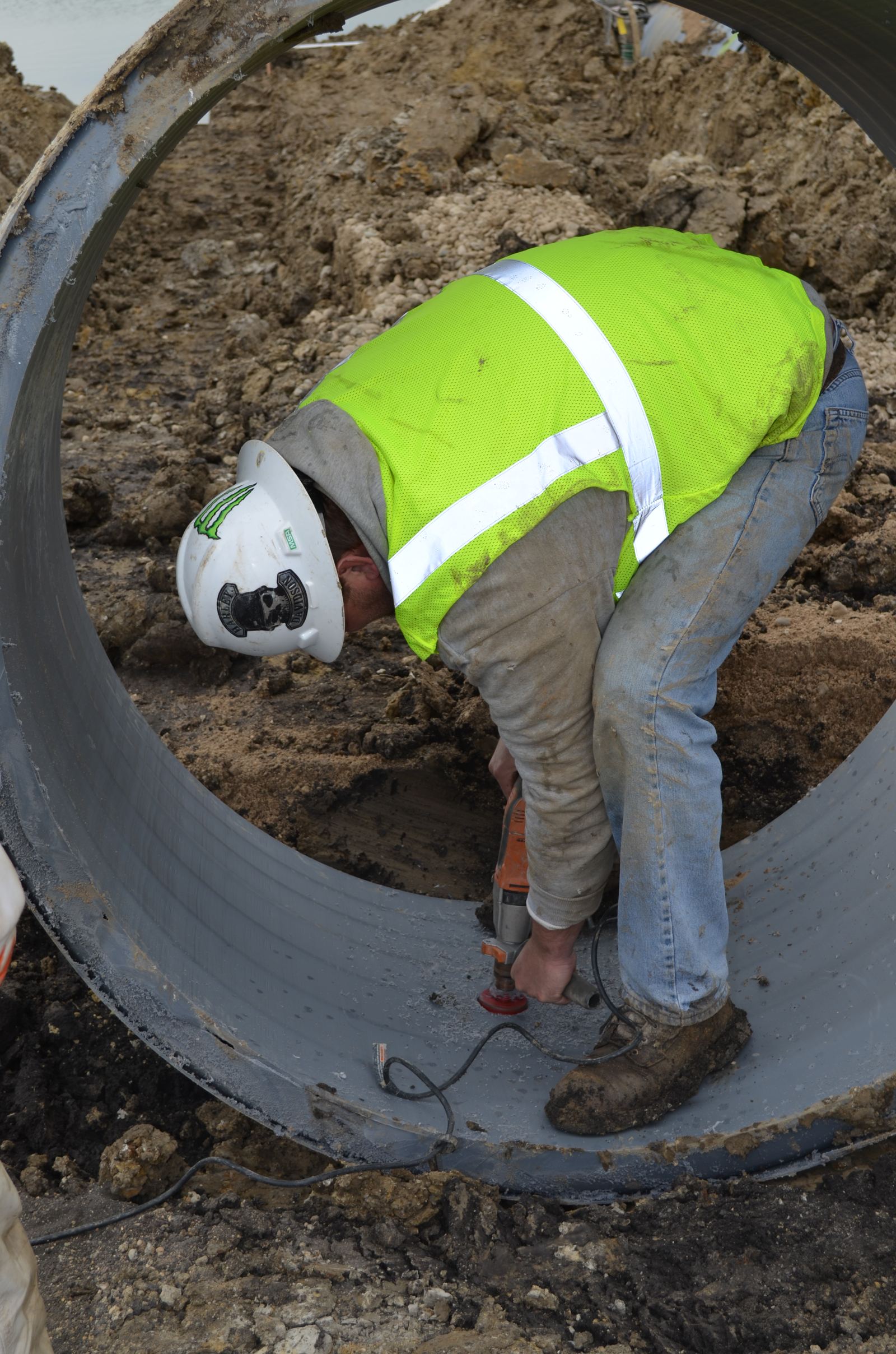 Worker inside a large-diameter pipe making a connection