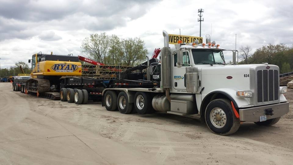 Ryan Contracting semi and lowboy trailer loaded with a RYAN excavator at the shop