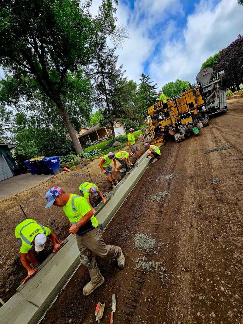 Crew finishing curb behind the slipform paver