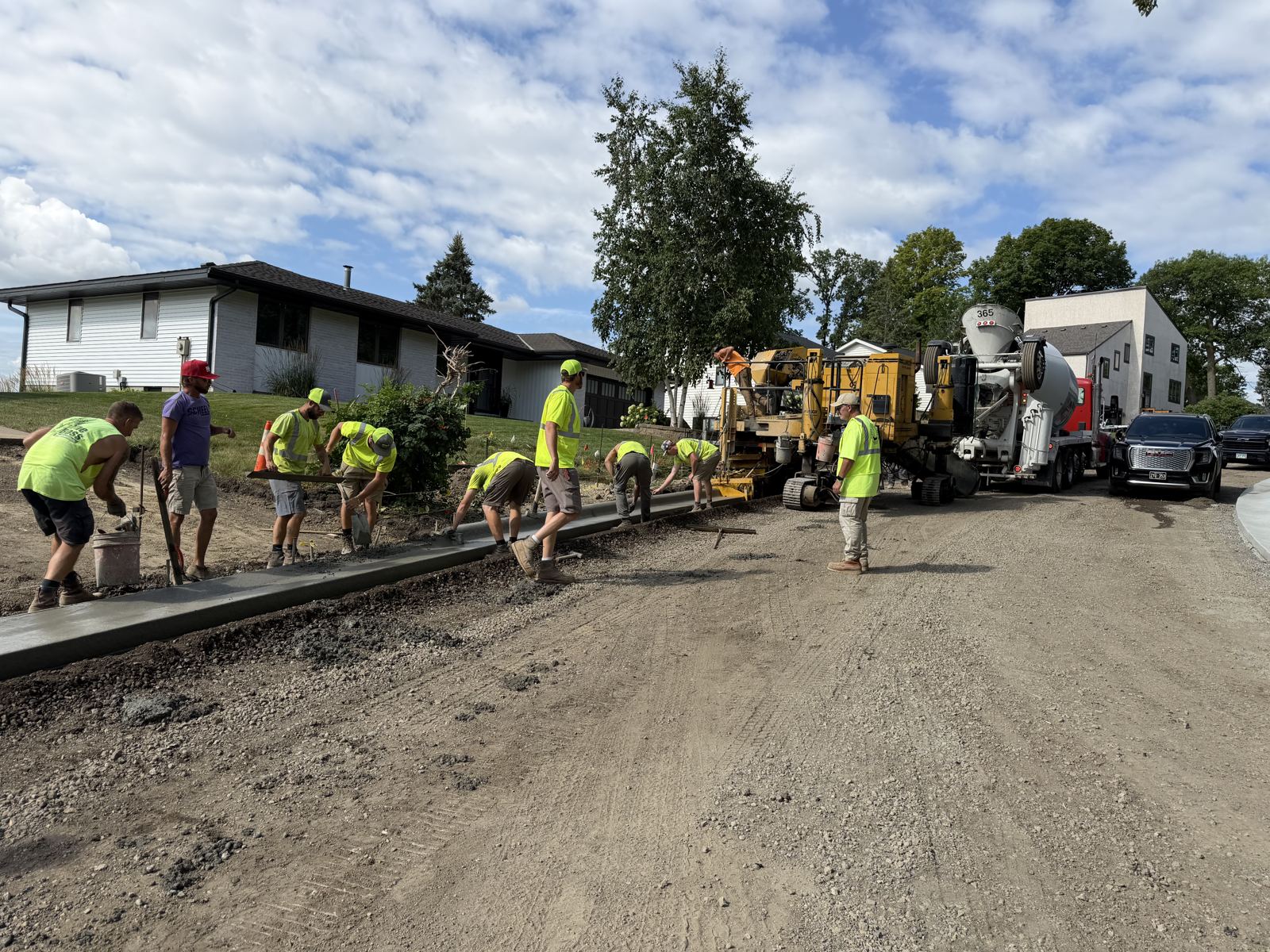 Slipform paver, ready-mix truck and finishing crew placing curb on a residential street