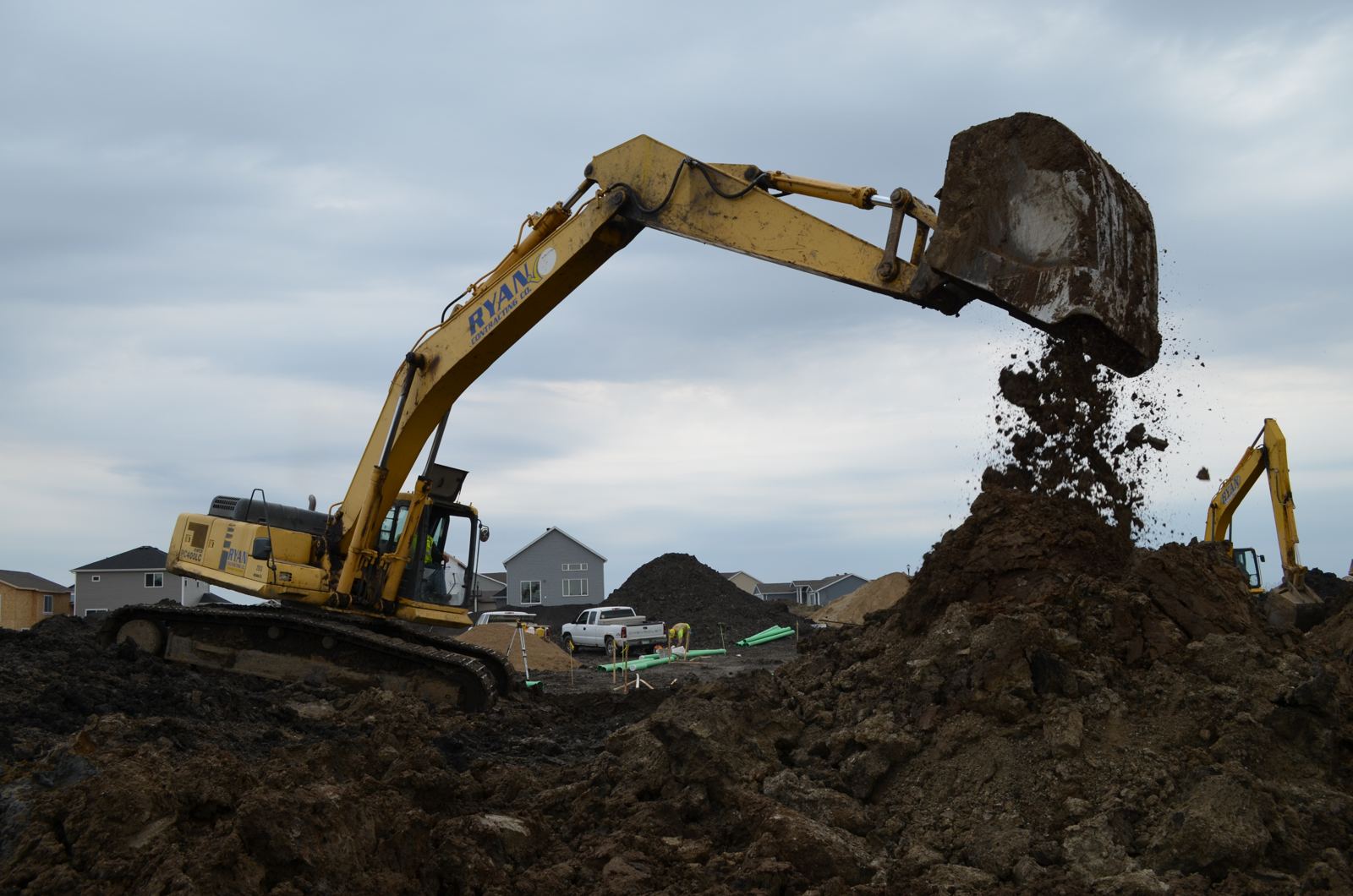 Excavator working in a new subdivision with homes in the background