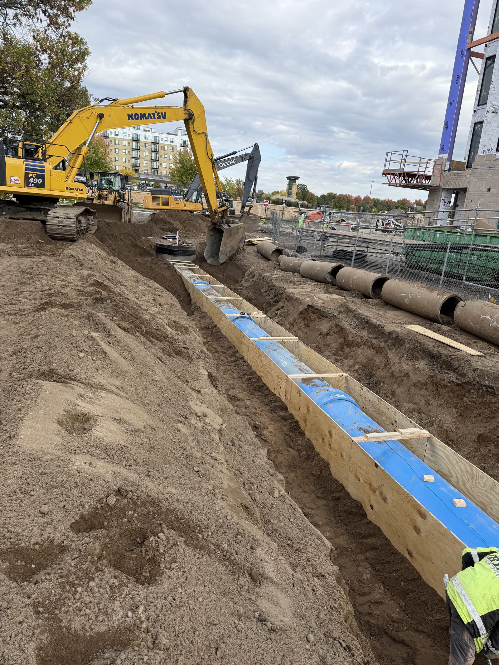 New blue watermain laid in a shored trench with a Komatsu PC490 excavator behind
